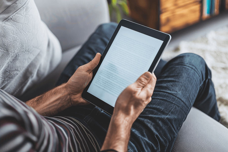 Adult man comfortably reading an e-book on a digital tablet