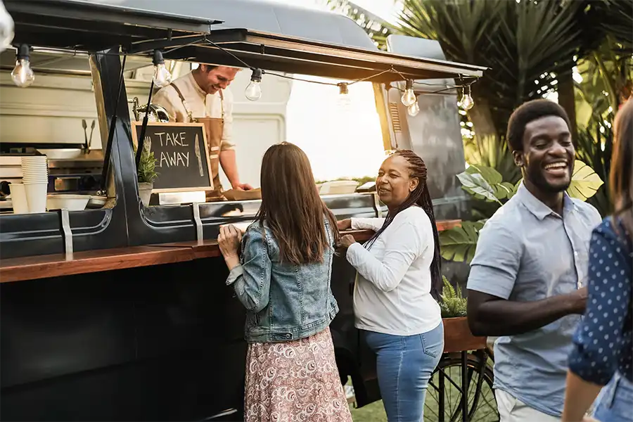 Two women chatting in line while ordering at a food truck