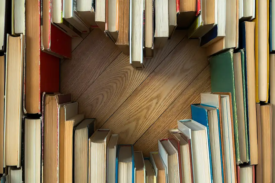 library books resting on a wooden table in the shape of a heart